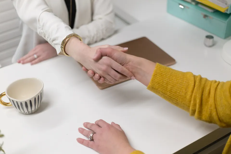 Poignée de main entre deux personnes autour d’un bureau