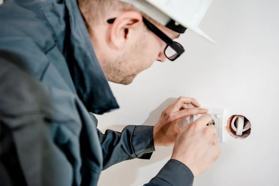 Électricien réparant une prise murale